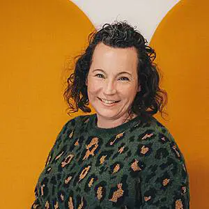 Woman smiling in green patterned sweater.