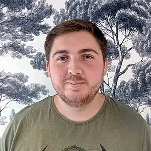 Man in green shirt with tree background.