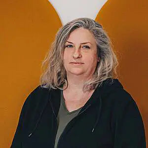 Woman posing in front of orange backdrop.