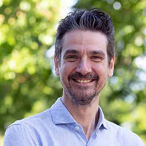 Man smiling in blue shirt outdoors.