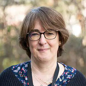 Smiling woman with glasses outdoors.