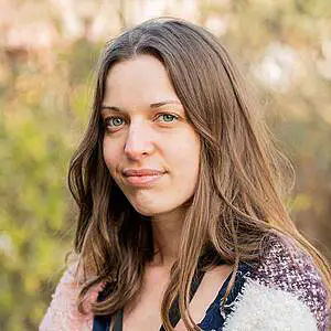Woman smiling in natural light outdoors.