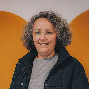 Smiling woman with glasses and curly hair.