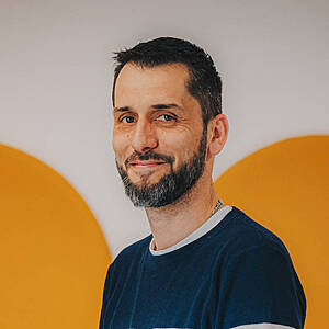 Man smiling in front of orange circles.