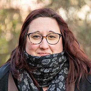 Woman wearing glasses and scarf smiling.