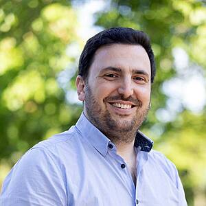 Man smiling outdoors in natural light.