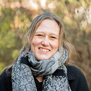 Woman smiling outdoors wearing scarf.
