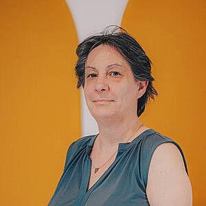 Woman in green blouse against orange background.