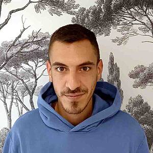 Man in blue hoodie with tree wallpaper.