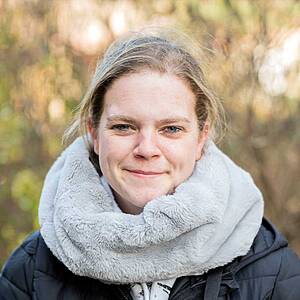 Woman smiling with a scarf outdoors.