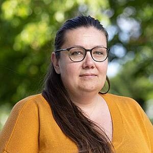 Woman in glasses with trees in background.