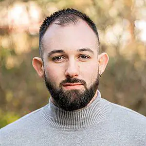 Man in grey turtleneck outdoors.
