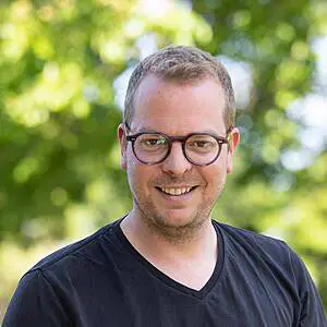 Smiling man with glasses outdoors.