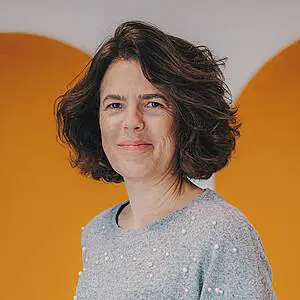 Woman smiling against orange background.