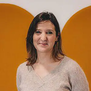Woman smiling in front of orange background.